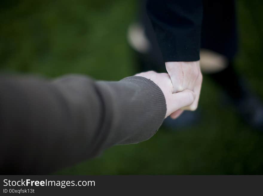 Close up of hands of man and woman with green grass background. Close up of hands of man and woman with green grass background