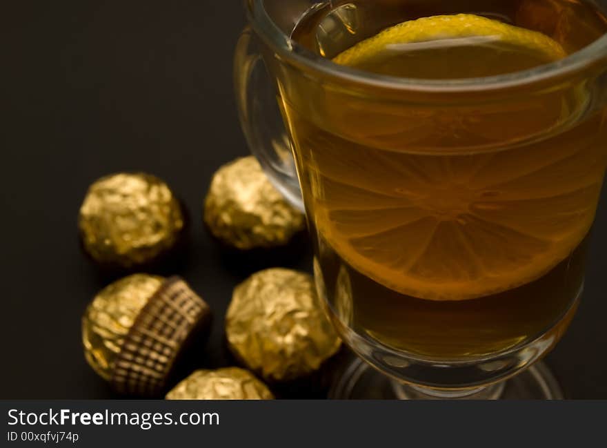 Tea with a lemon in glass chake and candies