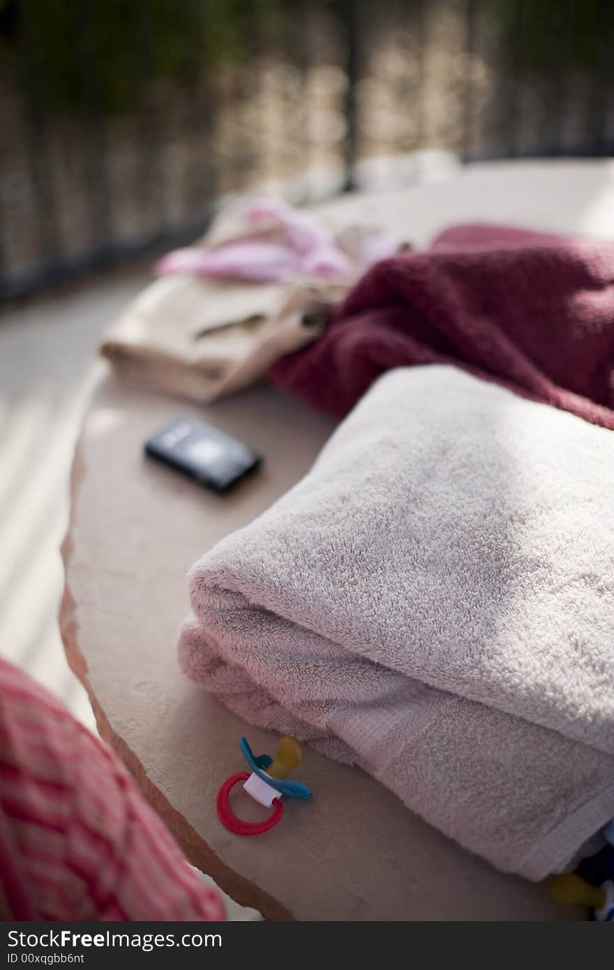 Towels, clothing, cellphone, and other objects on stone table