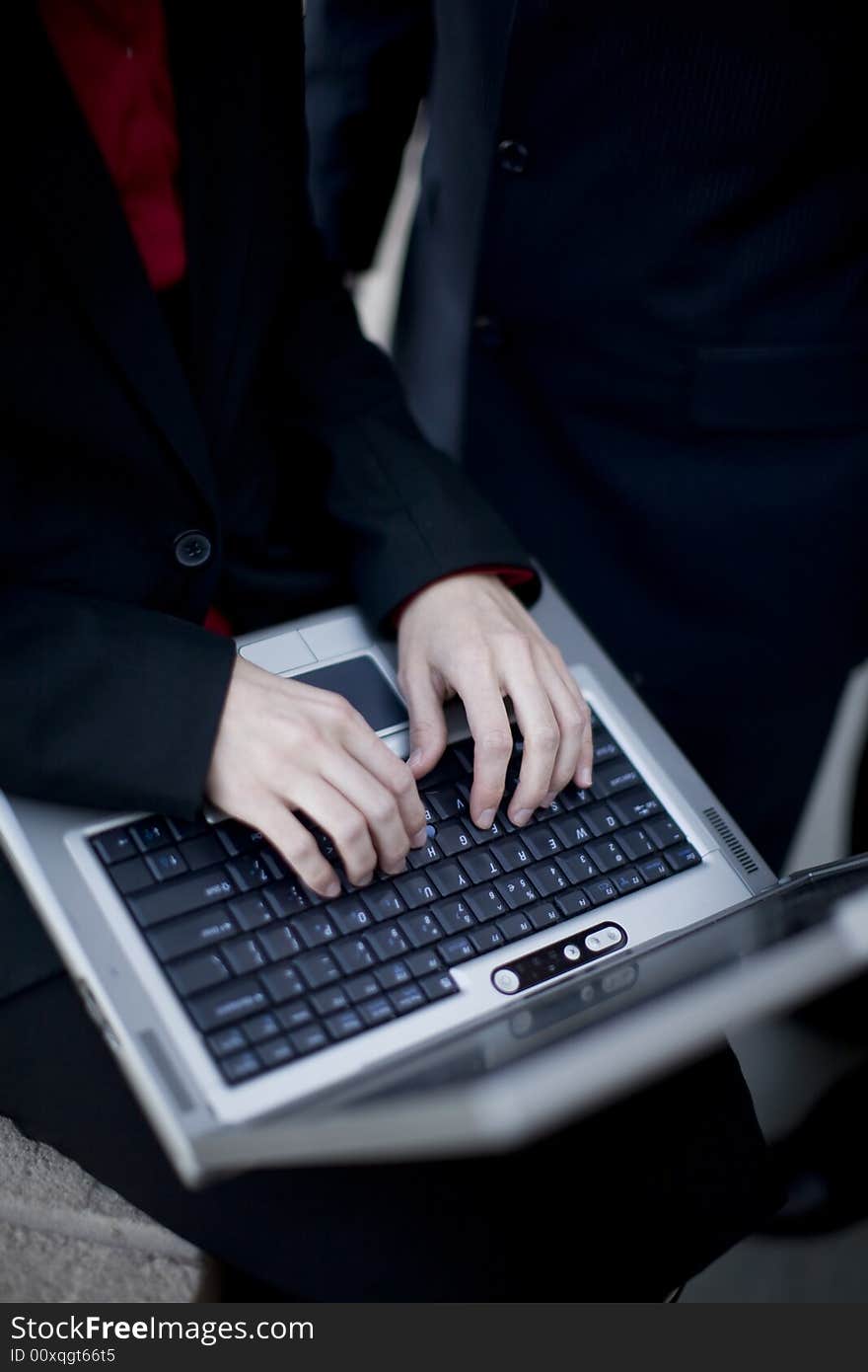 Businesswoman typing on laptop with businessman standing next to her. Businesswoman typing on laptop with businessman standing next to her