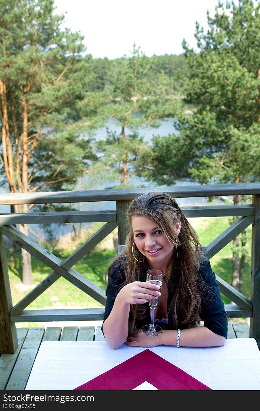 Young girl with glass of champagne on veranda