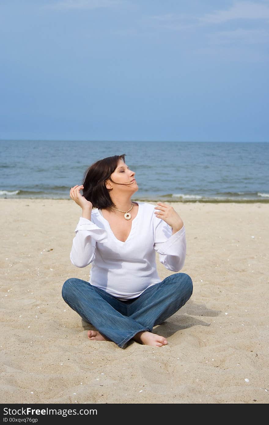 Pregnant woman sitting on the sand. Pregnant woman sitting on the sand