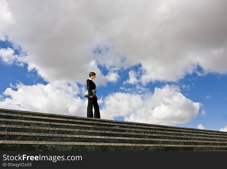 Businesswoman posing against huge cloudscape. Businesswoman posing against huge cloudscape.