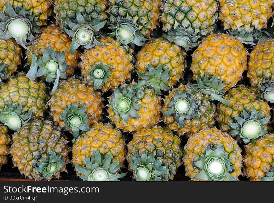 A pile of fresh fragrant and juicy golden pineapples. A pile of fresh fragrant and juicy golden pineapples.