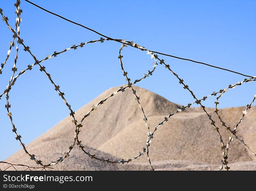 Desert hill after barbed wire on blue sky in background. Desert hill after barbed wire on blue sky in background