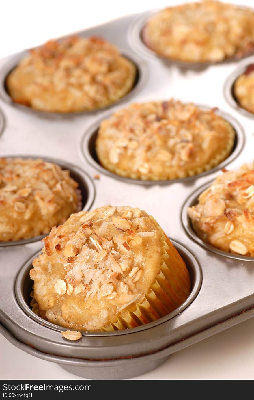 A muffin pan of freshly baked tropical pineapple muffins with coconut and nuts. A muffin pan of freshly baked tropical pineapple muffins with coconut and nuts