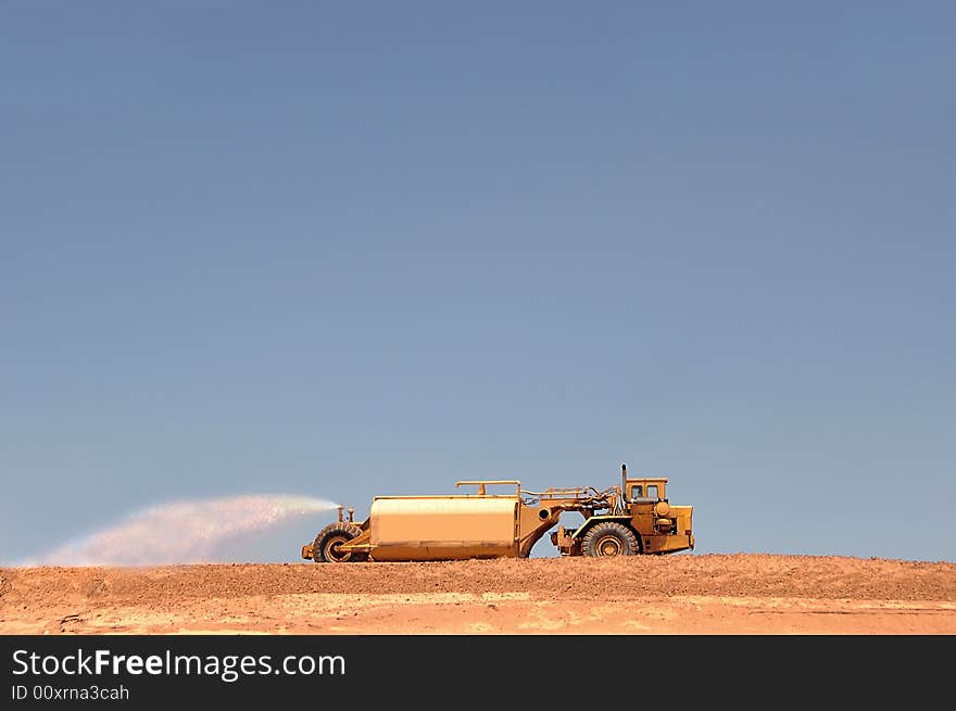 Large water truck watering down dirt on a construction pad