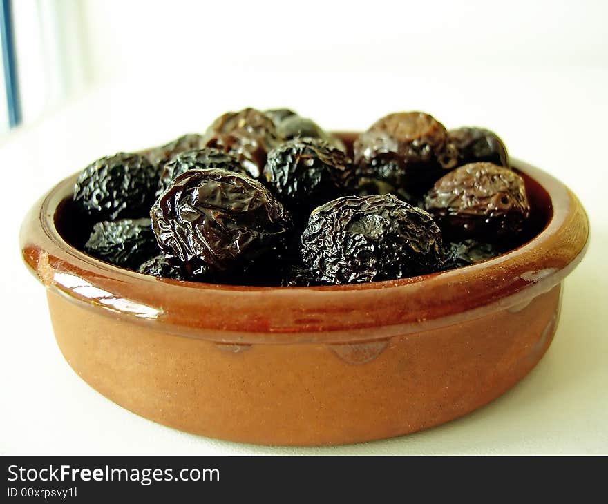 Bunch of dried black olives on a clay plate.