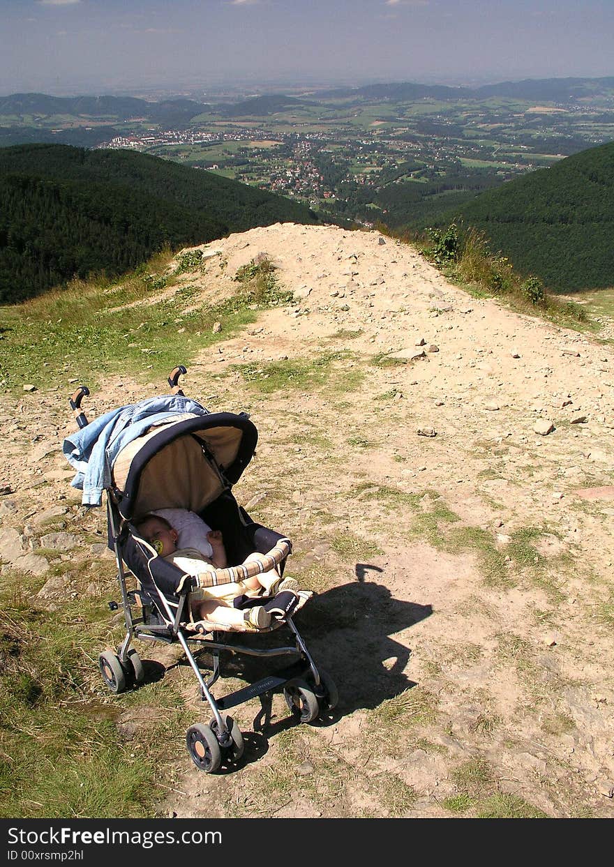A view of a baby stroller with child on the edge of a high scenic overlook.