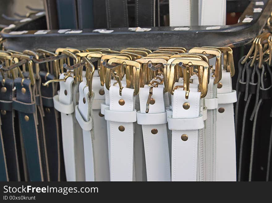 A close up shot of leather belts with gold buckles on a display stand