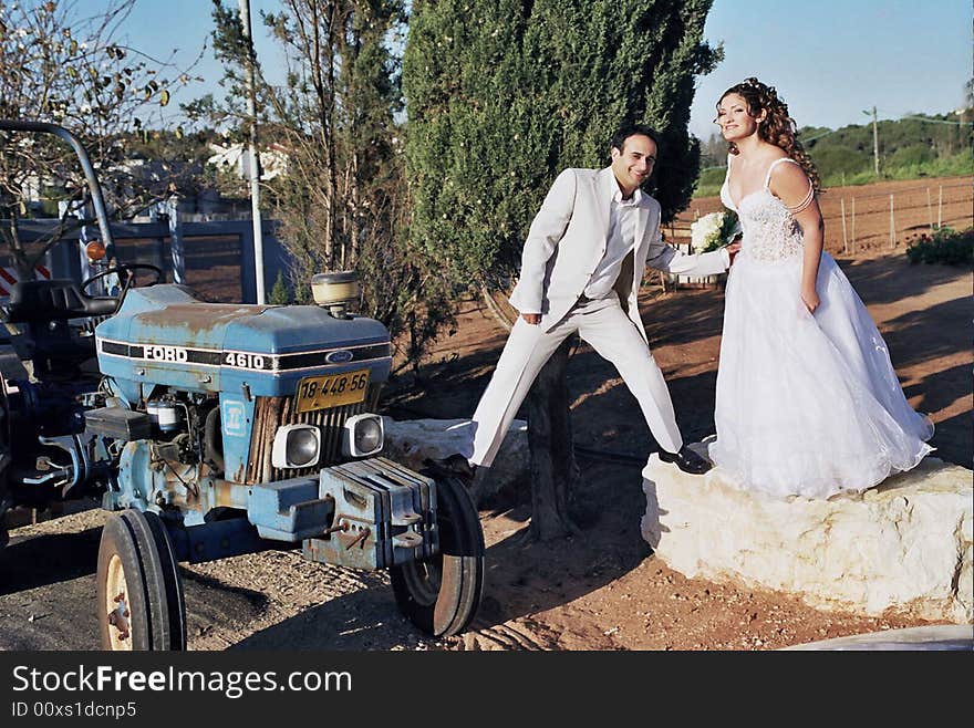 Groom and bride in the flower field holding wreath