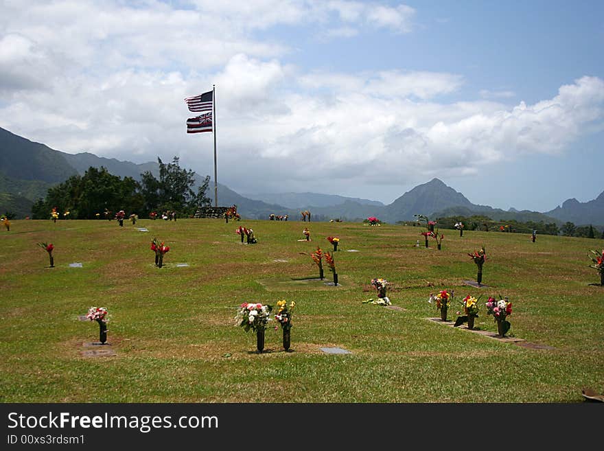 Gravesites are marked by flowers in a cemetery in the mountains of Oahu, Hawaii.