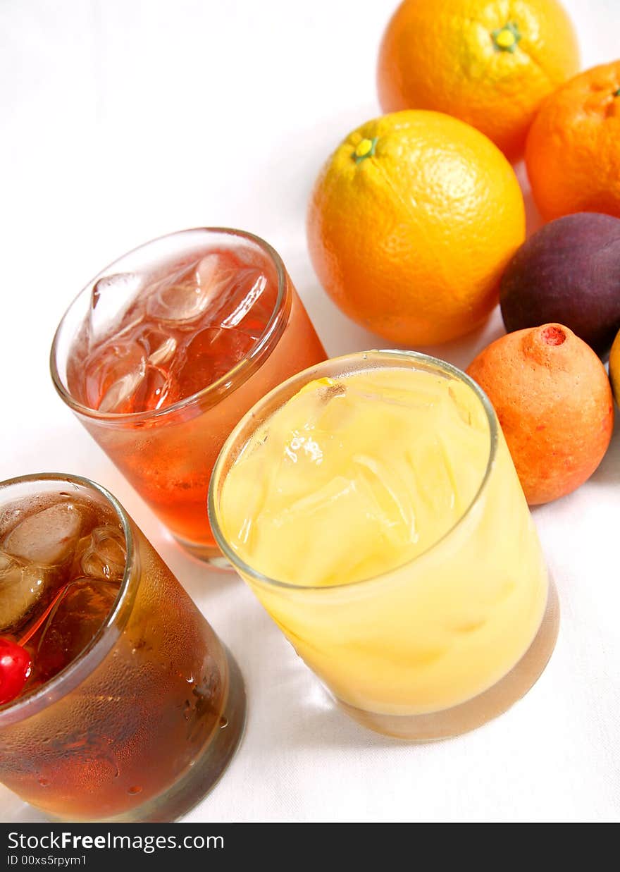 Three mixed drink on table. from left to right manhattan cocktail, malibu breeze cocktail, and screw driver cocktail. Three mixed drink on table. from left to right manhattan cocktail, malibu breeze cocktail, and screw driver cocktail