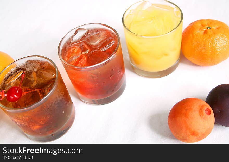 Three cocktails line up on white table. from left to right manhattan, malibu breeze, and screw driver. Three cocktails line up on white table. from left to right manhattan, malibu breeze, and screw driver