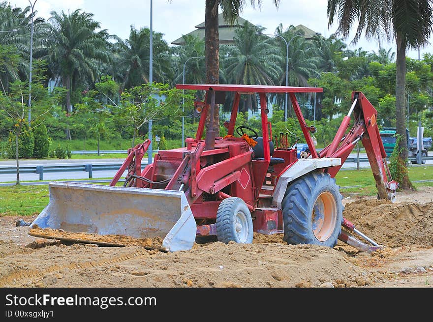 A red tractor busy with excavation work at a construction site. A red tractor busy with excavation work at a construction site