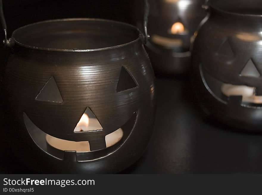 Three metal jack-o-lantern candle holders close-up.