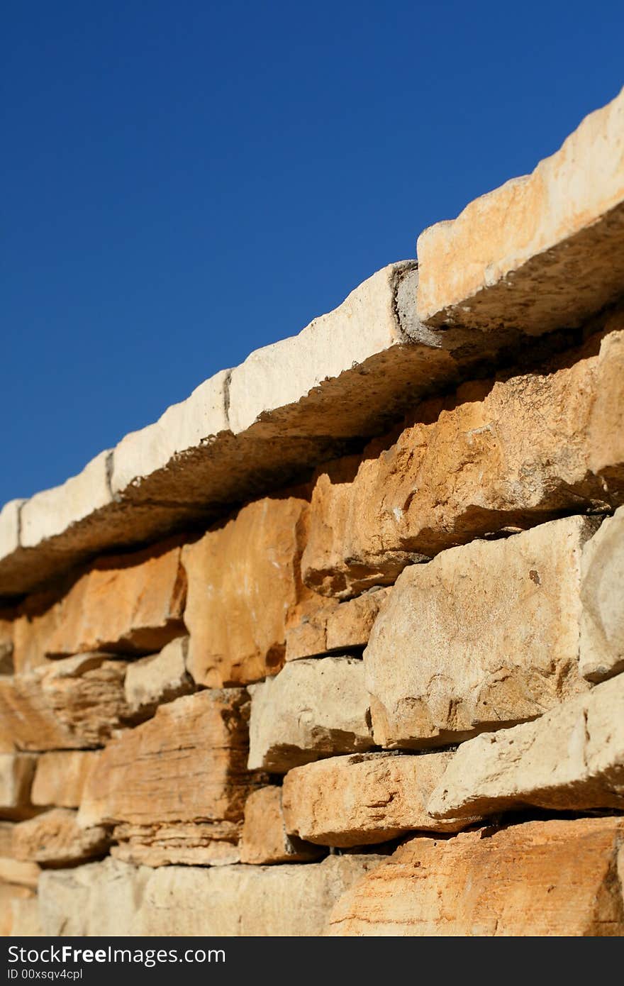 A worms eye view of a paved wall with a blue sky.