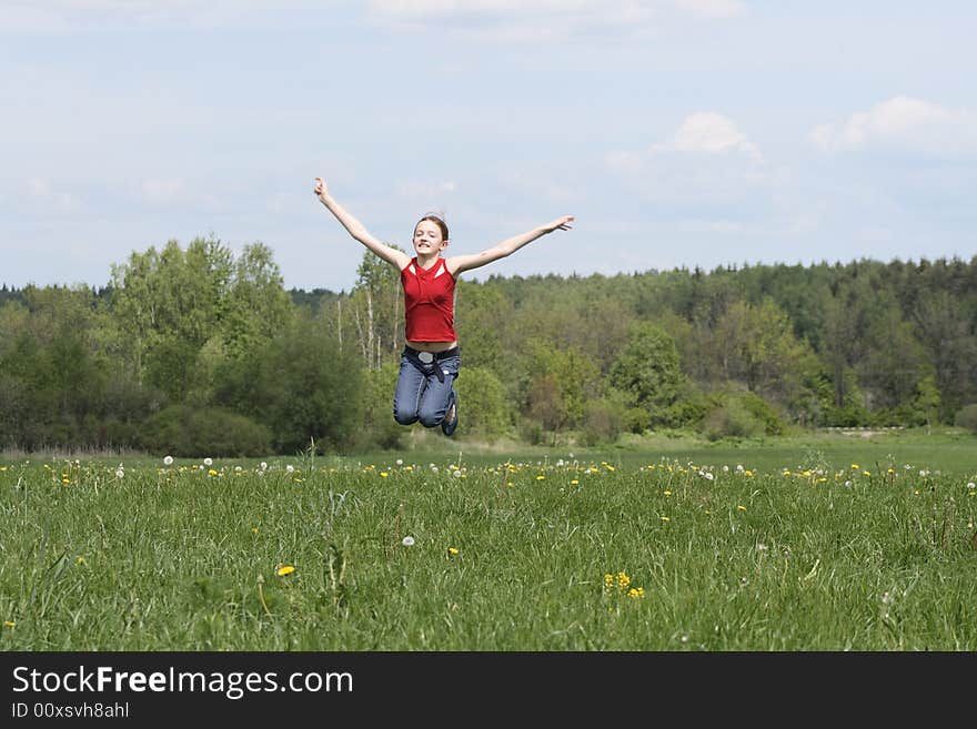 Nice young girl jumping on background with green field and blue sky. Nice young girl jumping on background with green field and blue sky