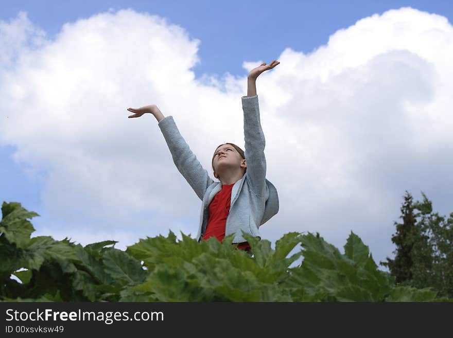 Nice young girl with hands up looking at the blue sky with clouds. Nice young girl with hands up looking at the blue sky with clouds