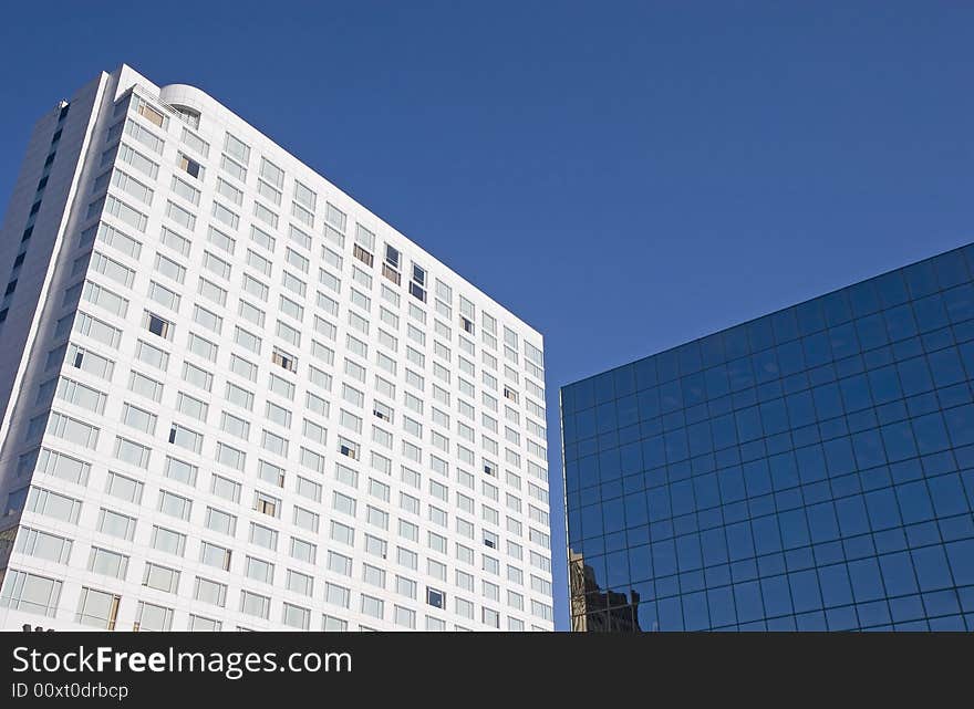 A large white hotel next to a blue glass office tower. A large white hotel next to a blue glass office tower