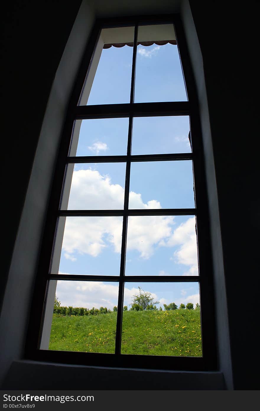 A closed window and view to a peaceful landscape with blue sky. A closed window and view to a peaceful landscape with blue sky