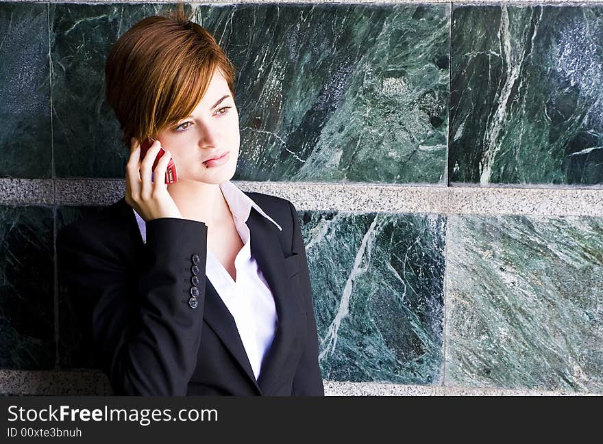 Beautiful businesswoman at phone over marble background.