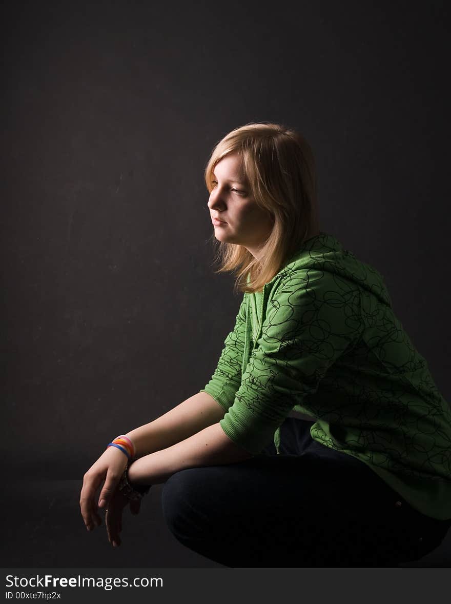 The young girl in green clothes on a black background. The young girl in green clothes on a black background.