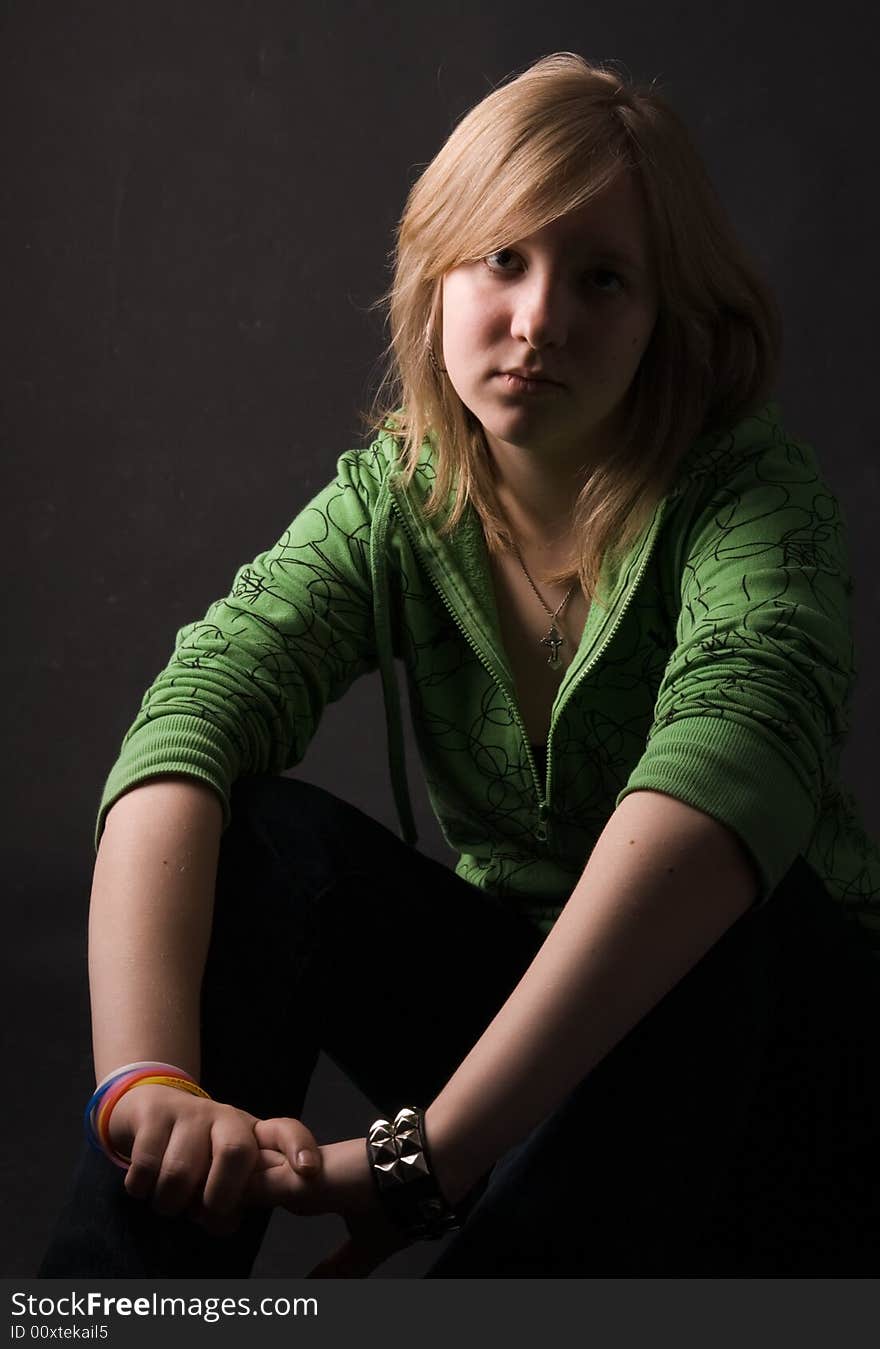 The young girl in green clothes on a black background. The young girl in green clothes on a black background.