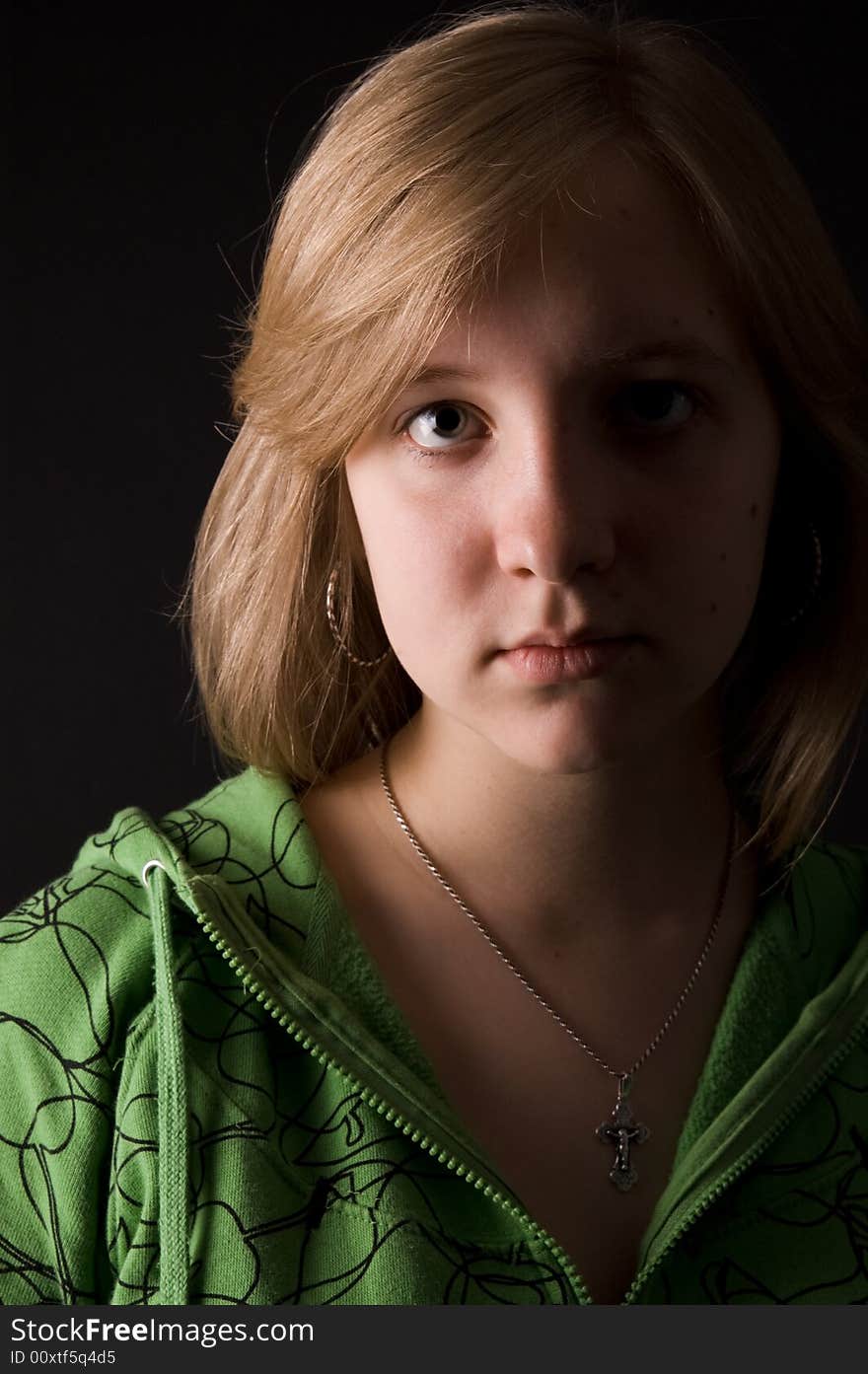 The young girl in green clothes on a black background. The young girl in green clothes on a black background.