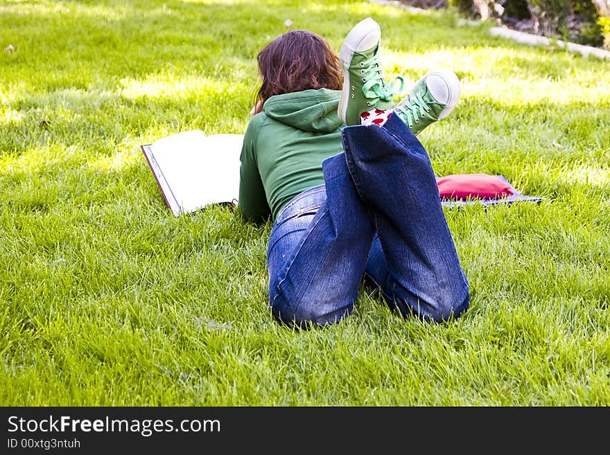 Young student reading on the grass in the park. Young student reading on the grass in the park.