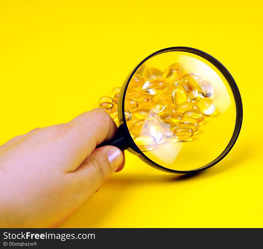 A view with some vitamins and magnifying glass over yellow background