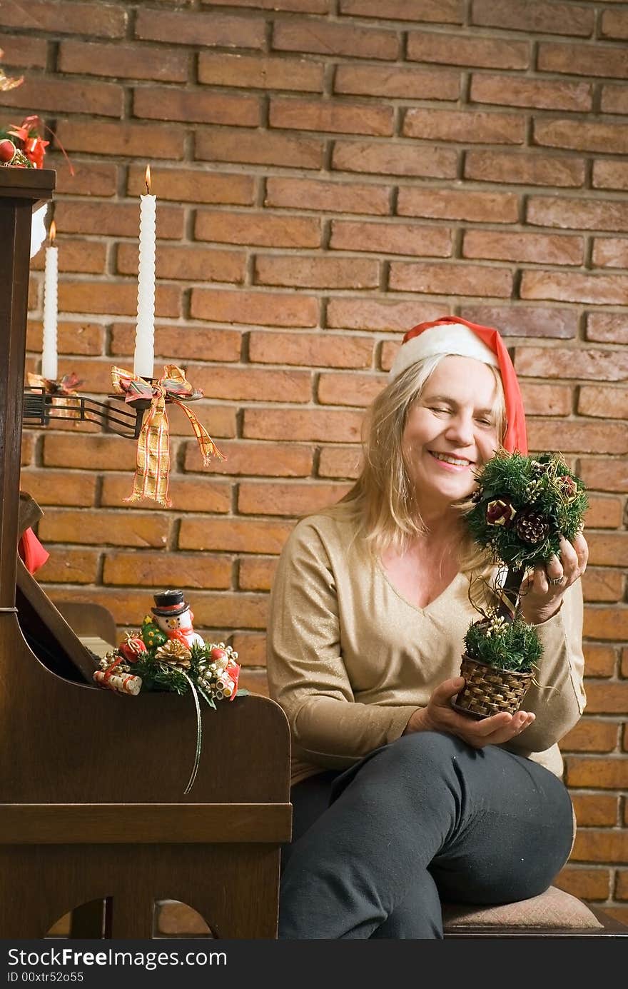 A women holding a Christmas decoration sitting by a piano with Christmas candles. A women holding a Christmas decoration sitting by a piano with Christmas candles.