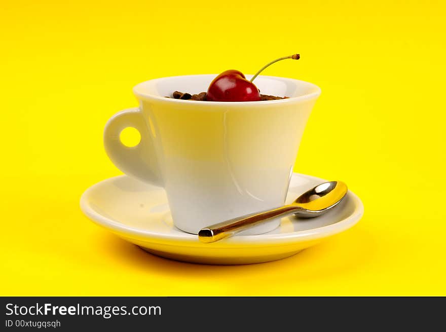 Macro studio shot of a cup of coffee beans and cherry.