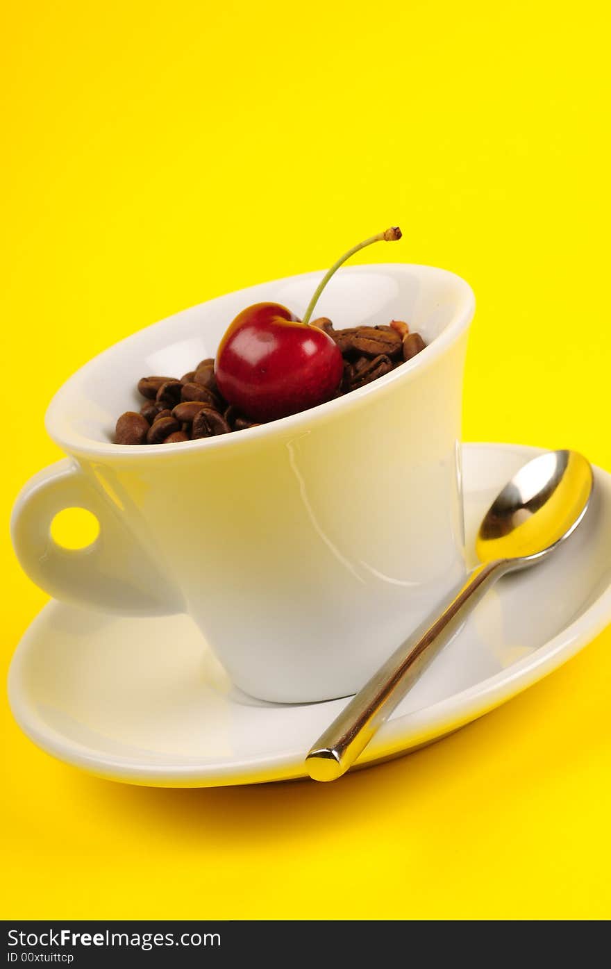 Macro studio shot of a cup of coffee beans and cherry.