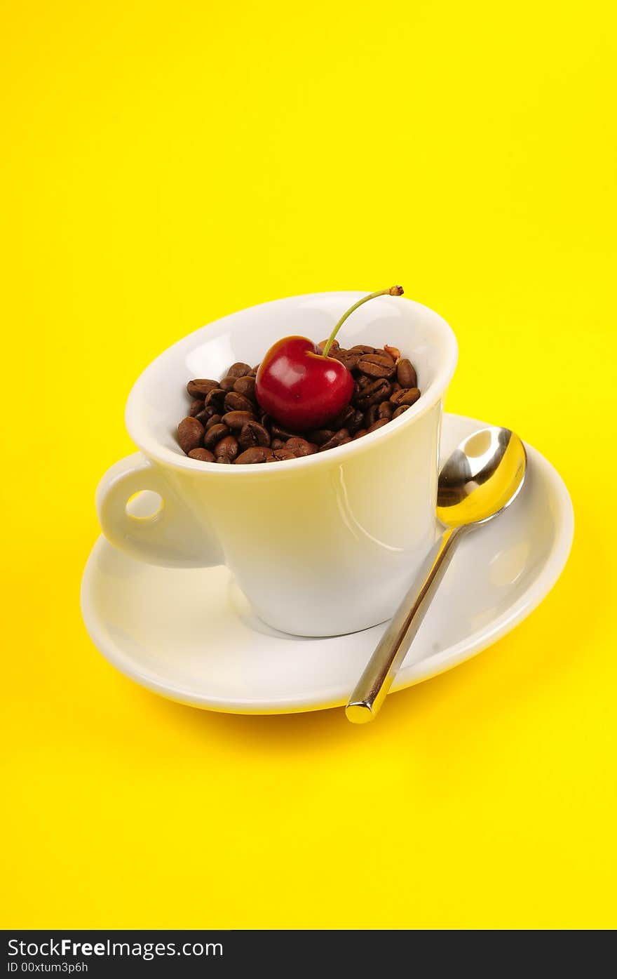 Macro studio shot of a cup of coffee beans and cherry.