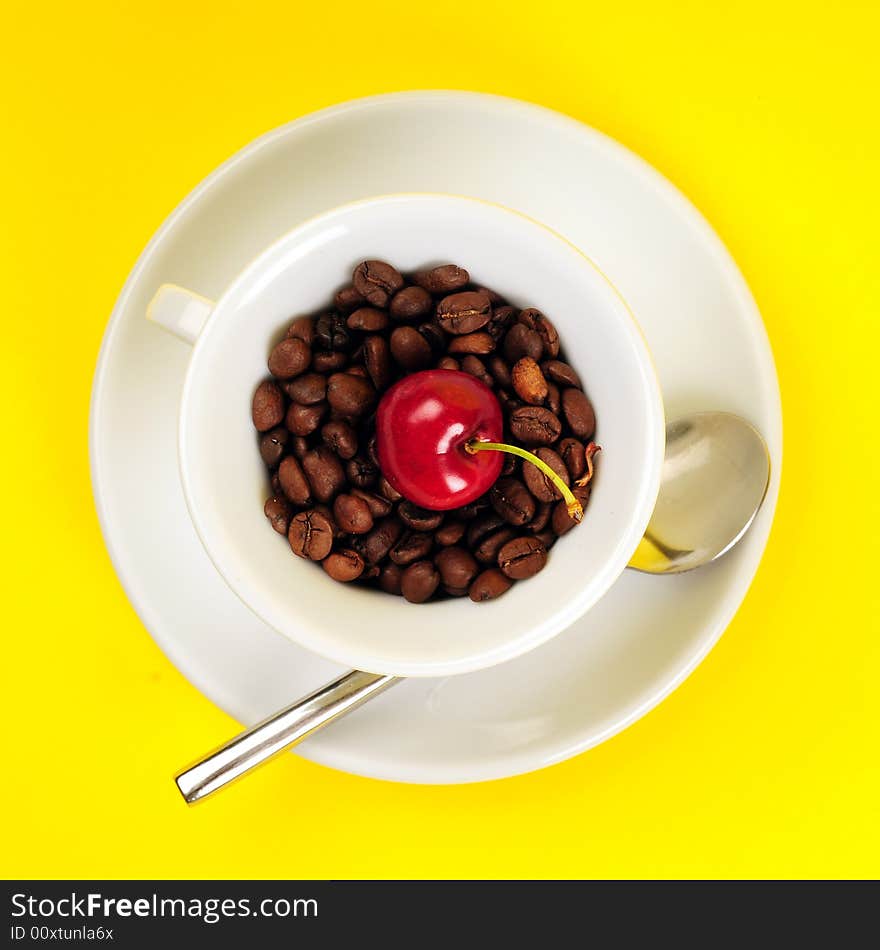 Macro studio shot of a cup of coffee beans and cherry.