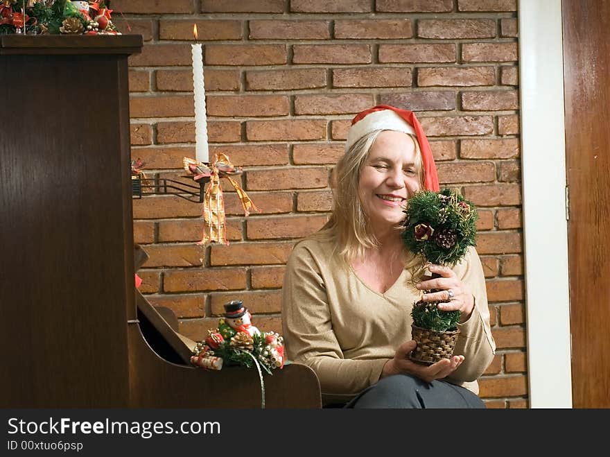 A women holding a Christmas decoration sitting by a piano with Christmas candles. A women holding a Christmas decoration sitting by a piano with Christmas candles.