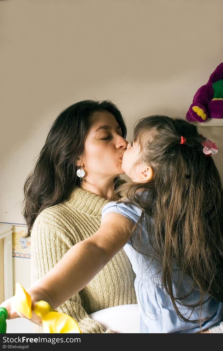 A mother kissing her daughter. A mother kissing her daughter.