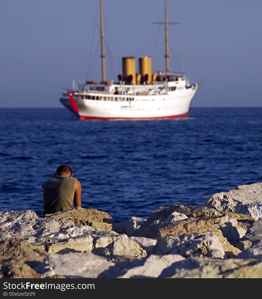 A lonely boy looks out at a departing ship. A lonely boy looks out at a departing ship