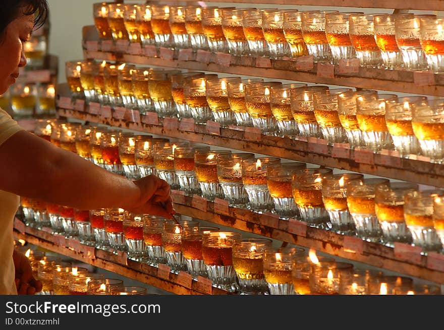 A volunteer helping to keep the flames of the wesak day oil lamp burning. A volunteer helping to keep the flames of the wesak day oil lamp burning