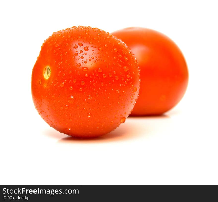 The ripe tomatoes covered by drops of water is isolated on white