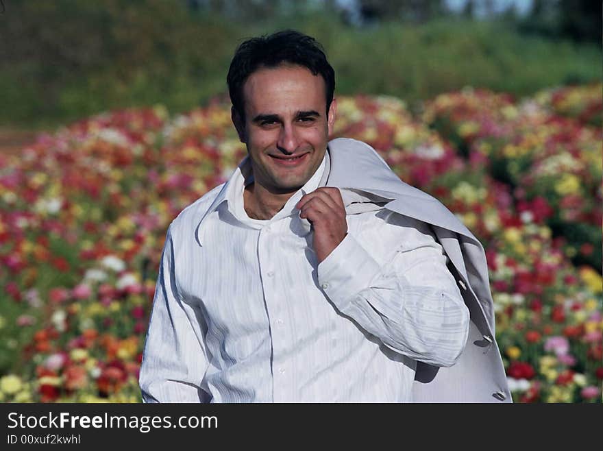 Groom in the flower field holding his coat