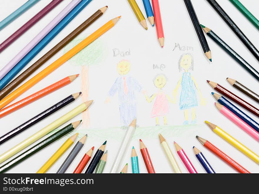 Multicolored pencils at a white paper with a child's family picture. Multicolored pencils at a white paper with a child's family picture