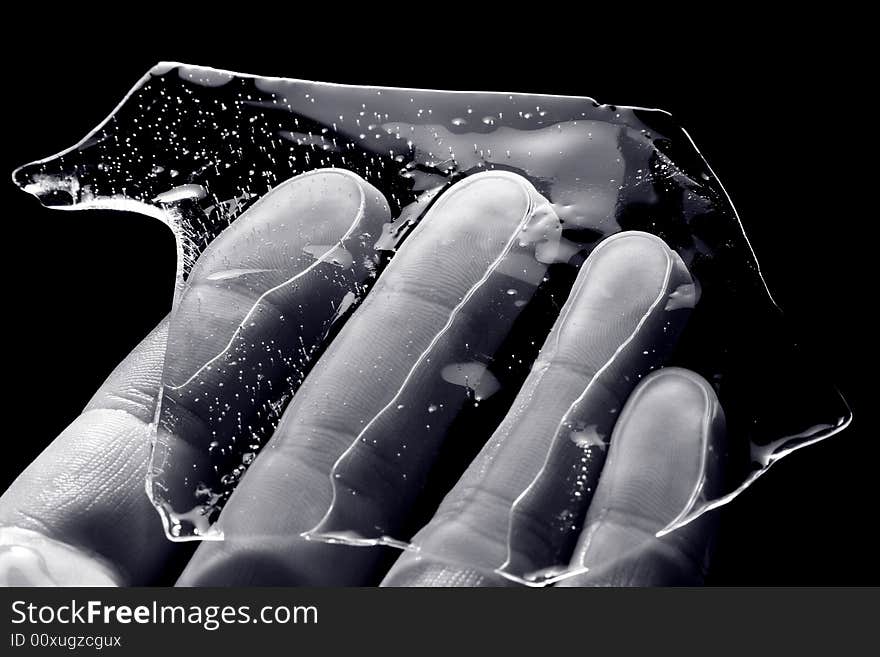 Hand, keeping splinter of ice on black background