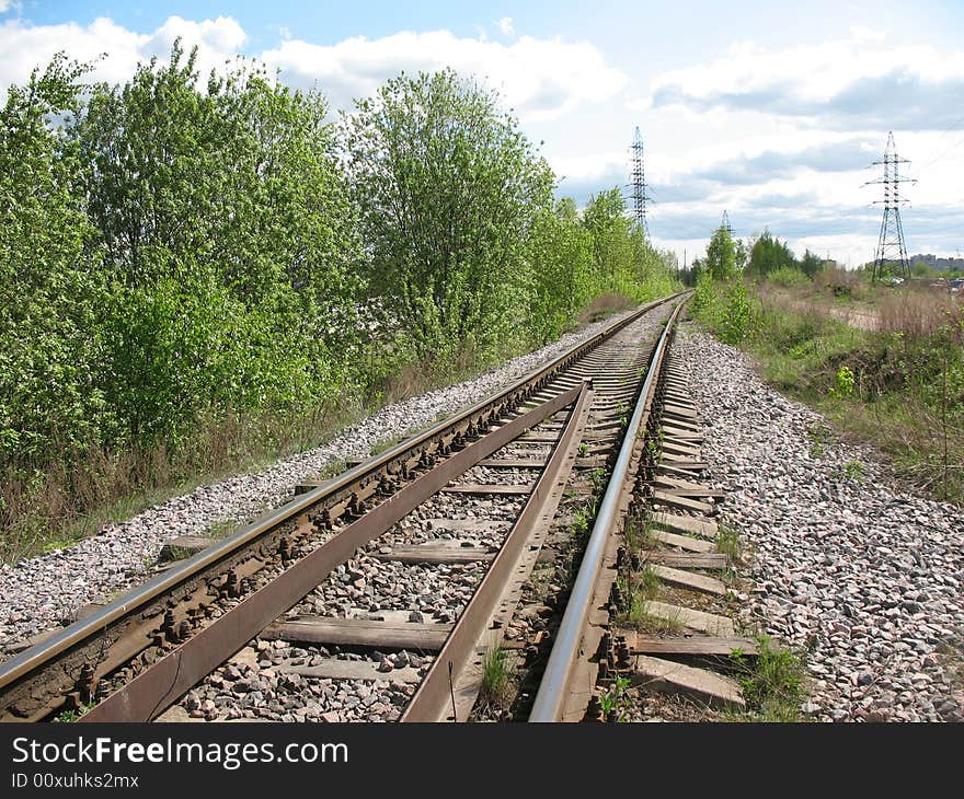 A running away railroad. A permanent way, a macadam, a sleepers and rails. A skylineand a overcast sky.