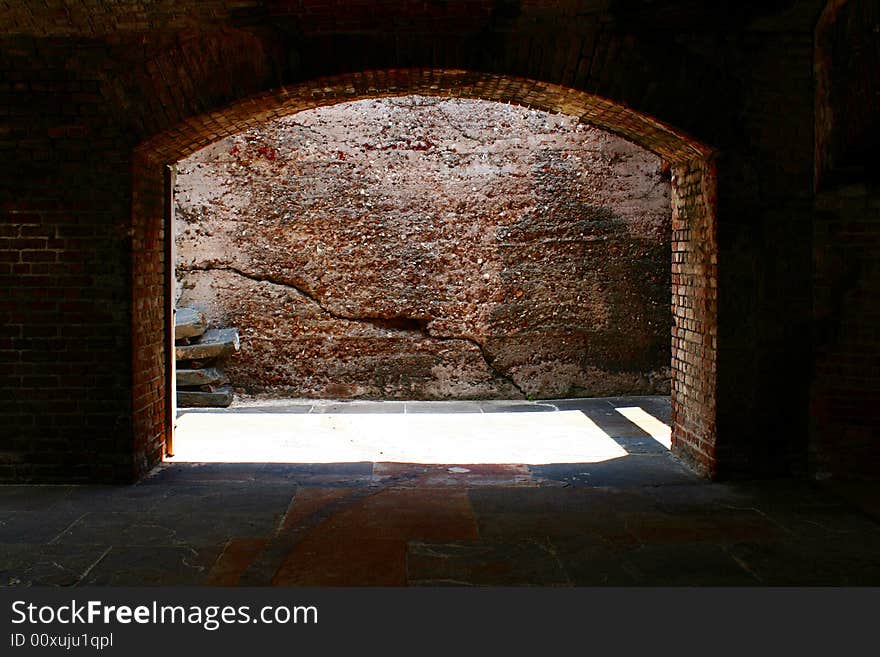 A brick arch way with daylight shinny through.