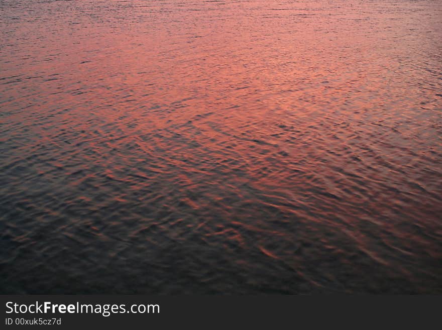 The ocean water reflecting the pink sky during sunset. The ocean water reflecting the pink sky during sunset.