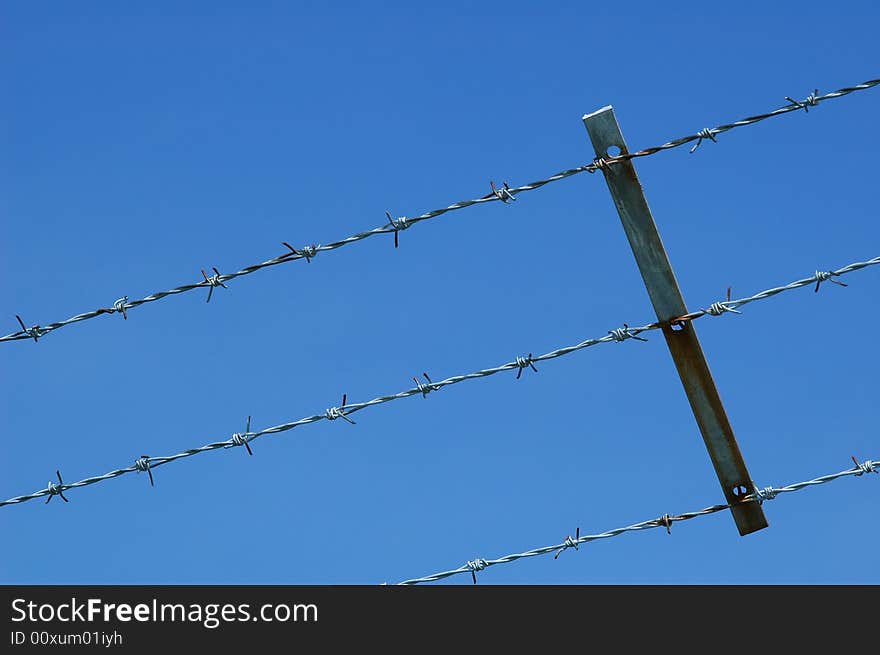 Barbed wire fencing against blue sky