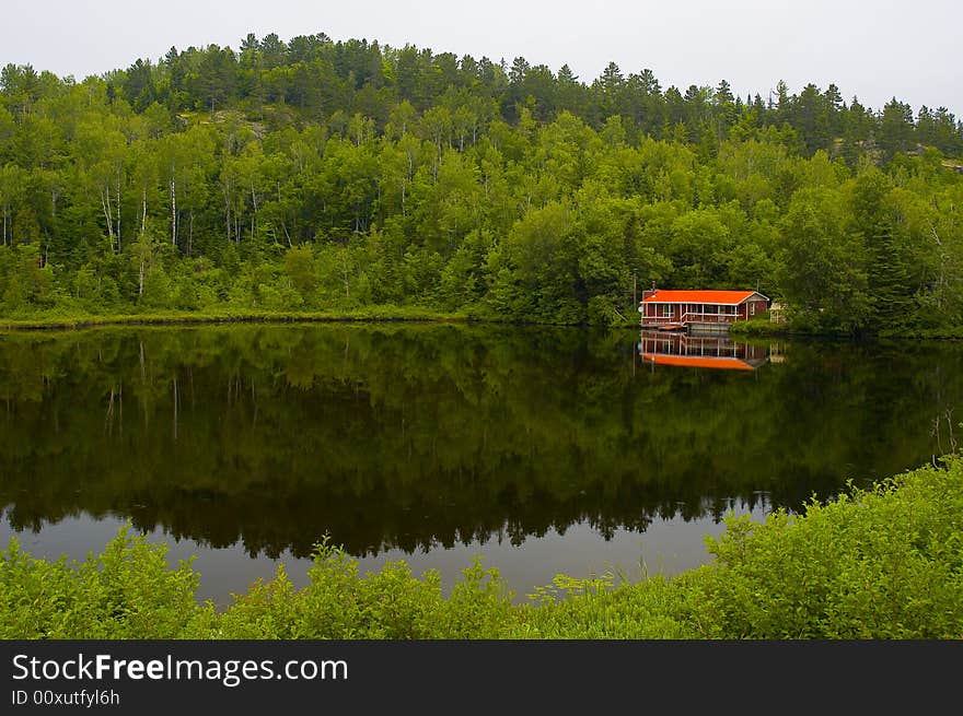 A small red house by a calm lake