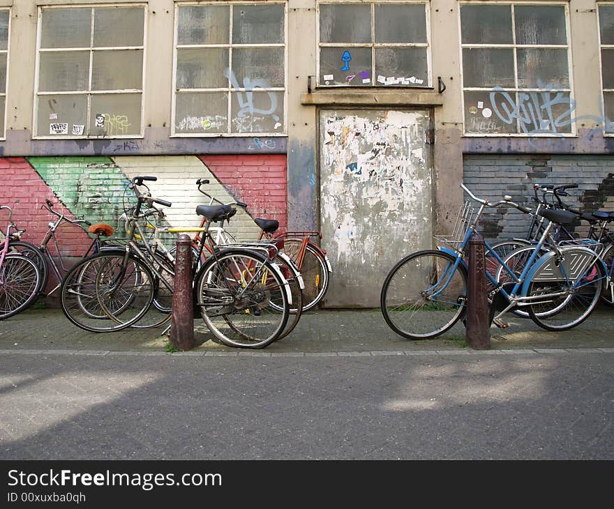 Empty bicycles in front of a colored wall.